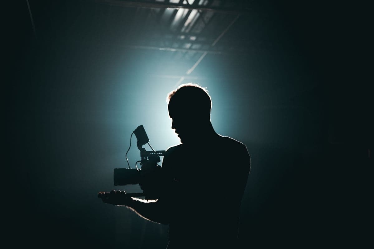 Camera operator silhouetted in a studio
